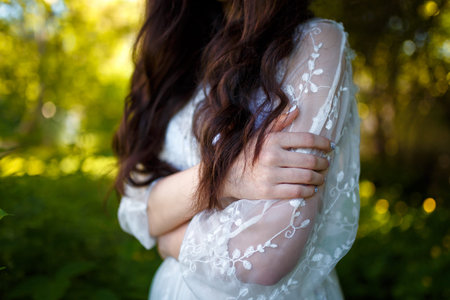 Hands of teenager girl in white dress with long dark hair in apple garden. Spring blooming and youth concept.の写真素材