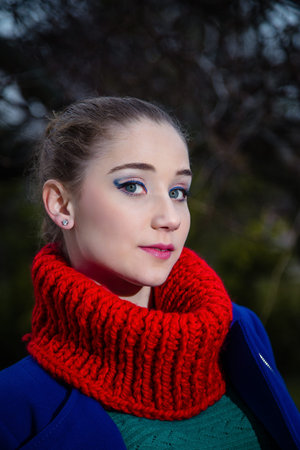 Young girl in red knitted snood scarf in blue coat. Female autumn and winter clothing and...