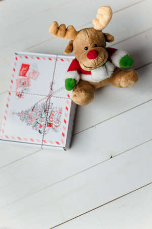 Christmas present box and reindeer toy on white wooden background. Copy space. Vertical shot.の写真素材