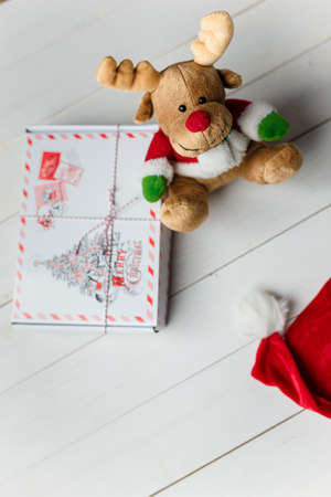 Christmas present box and reindeer toy on white wooden background. Copy space. Vertical shot.の写真素材