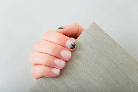 Female hands with fir-tree forest manicure holding leather covered album or notebook on white background. Christmas or winter nail art. Hands care, fingernails design, beauty and health concept.の写真素材