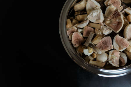 Cut fresh forest champignon mushrooms in a metallic bowl on black wooden table. Healthy vegetarian organic food. Diet concept. Top view, place for text.の写真素材