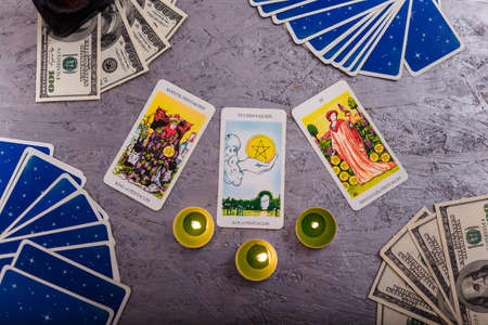 Divination cards alignment with money and green candles. Mystery, astrology, fortune telling, belief and wealth concept.の写真素材