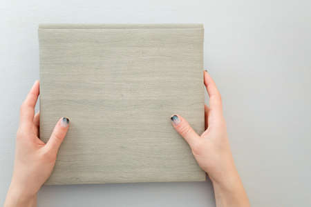 Female hands with fir-tree forest manicure holding leather covered album or notebook on white background. Christmas or winter nail art. Hands care, fingernails design, beauty and health concept.の写真素材