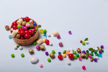 Close up of wooden bowl of multicolored beads for sewing and embroidery. Set of materials for...