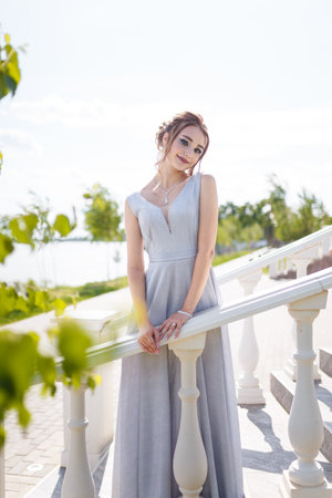 Beautiful girl in tender prom dress on stairs background. Female portrait on spring landscape.の写真素材