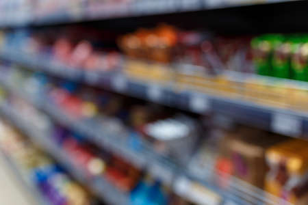 Unfocused shot of supermarket interior. Blurry hypermarket, mall or shopping center background. Rows and shelves of grocery department.の写真素材