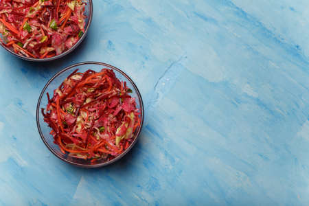 Two bowls of salad called Brush. Beetroot, carrots and cabbage cut into thin strips on blue wooden background. Vegetarian, organic, healthy food, diet, nutrition. Top view, copy space.の写真素材