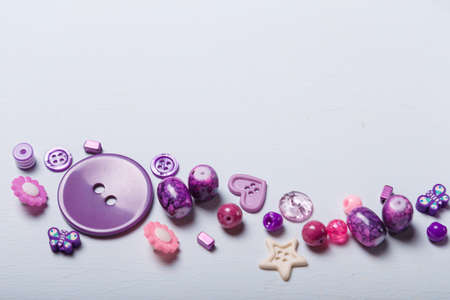 Close up shot of beads and buttons for sewing and embroidery. Purple set of materials for handcraft, making of bijouterie and accessories. White background, copy space.の写真素材