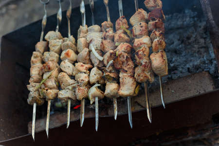 Marinaded pork meat pieces on skewers frying over bonfire. Kebab or traditional shashlik cooking with lot of smoke.の写真素材