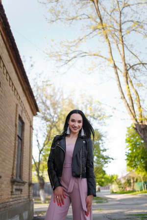 Pretty long-haired young woman in black leather jacket posing on the street, lifestyle portrait.の写真素材