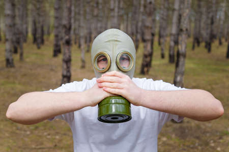 Portrait of man taking off a gas mask in forest. Enviromental protection, ecology, Earth saving, pollution prevention, safeness and hope concept.の写真素材