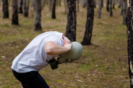 Man taking off gas mask in pine forest. Enviromental protection, ecology, Earth saving, pollution prevention, crisis, health concept.の写真素材