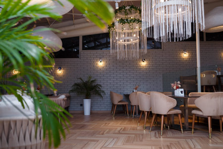 Izmail, Ukraine. January 2021. Modern restaurant interior with tables, soft arm-chairs, green potted plants, decorative light.のeditorial素材