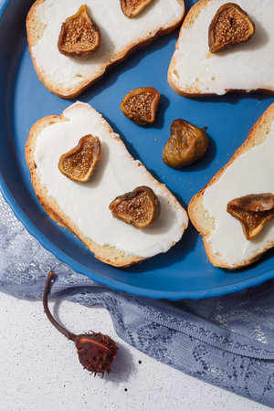 Closeup vertical shot of cream cheese and figs sandwiches on blue plate. Seasonal fruit and farm...