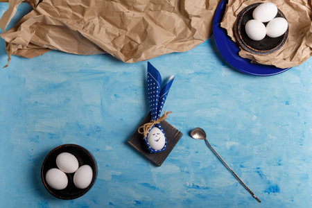 Eggs on brown paper and blue plate. Easter bunny made from egg and polka dot napkin ears, spoon on...