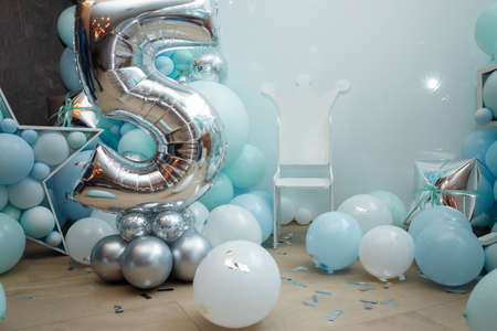 Blue balloons for boy happy birthday party. Number 5 for five years old child. Festive decorative elements, photo zone with star and chair.の写真素材