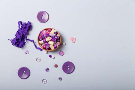 Close up of box of beads and buttons, tape or ribbon for sewing and embroidery. Purple set of materials for handcraft, making of bijouterie and accessories. White background, copy space.の写真素材