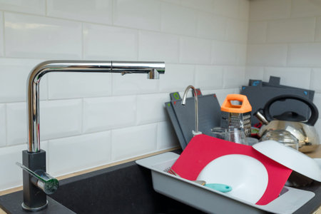 soft focused shot of water tap, crane on foreground and unfocused dirty dishes in sink on kitchen...