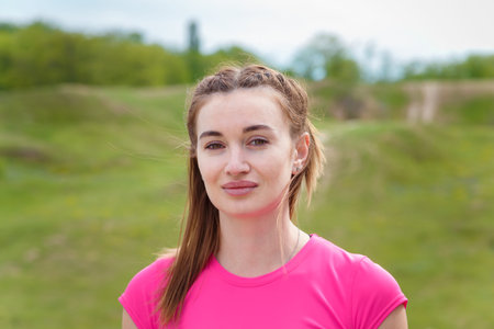 Portrait of young smiling woman in sportswear outdoors getting ready for physical training.の写真素材
