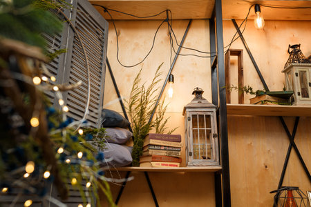 Izmail, Ukraine. December 2020. Rustic style Christmas festive decorations, fresh spruce thuja, fir branches, lantern, bulb, books. Warm garland lights boke. Eco-friendly decorative elements.のeditorial素材