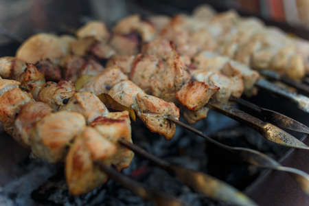 Soft focused shot of marinaded pork meat pieces on skewers frying over bonfire. Kebab or traditional shashlik cooking with lot of smoke.の写真素材