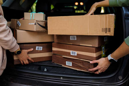 Izmail, Ukraine, May 2021. Two women taking carton packages, parcels out of car. Close up only hands, back viewのeditorial素材