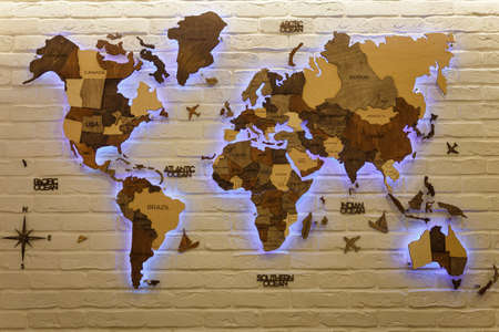 Izmail, Ukraine. March 2021. Wooden decorative world map with purple neon backlight on apartment wall. Modern interior design.のeditorial素材