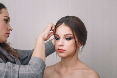 Stylist doing hairstyle for beautiful teenage girl. Hairstyle, beauty standards, fashion concept. Close up shot.の写真素材
