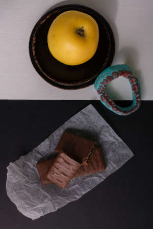 Caries prevention, teeth health. Fresh fruit, apple against unhealthy sweets, chocolate. Healthy eating, diet for teeth and oral cavityの写真素材