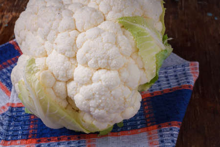 Cauliflower head on towel, wooden background. Organic farm vegetables, seasonal harvest, healthy eating, vegan diet. Close upの写真素材