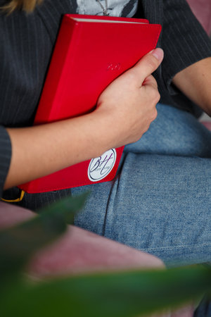 Izmail, Ukraine. May 2021. Female hand holding red notebook, diary planner. Woman in jeans, jacket...