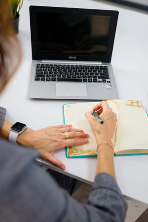 Izmail, Ukraine. May 2021. Business woman working in office, writing in notebook back to camera....