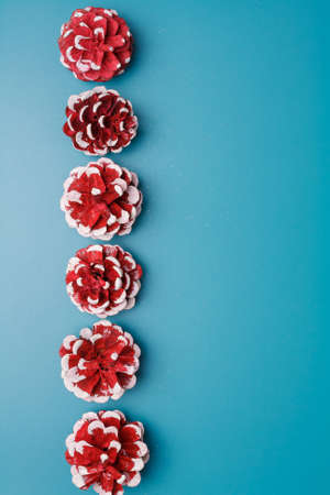 Merry Christmas, Happy New Year postcard, festive blue background, red white painted pine cones. Copy space, place for textの写真素材