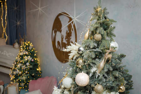 Izmail, Ukraine. December 2020. Room decorated for Christmas, New Year celebration. Pink sofa, piano, two fir-trees, wooden picture with reindeers. Holiday spirit. Modern interior.のeditorial素材
