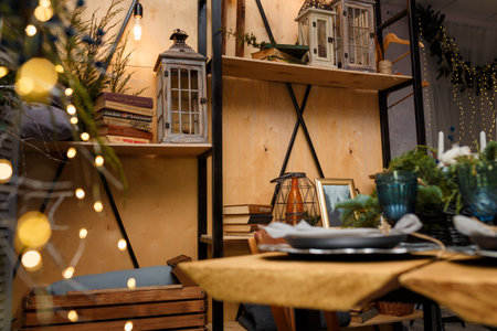 Izmail, Ukraine. December 2020. Rustic style Christmas festive decorations, fresh spruce thuja, fir branches, lantern, bulb, books. Warm garland lights boke. Eco-friendly decorative elements.のeditorial素材