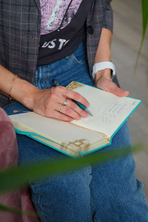 Izmail, Ukraine. May 2021. Soft focused vertical shot of business woman in gray jacket and jeans holding pen, notebook. Freelanceのeditorial素材