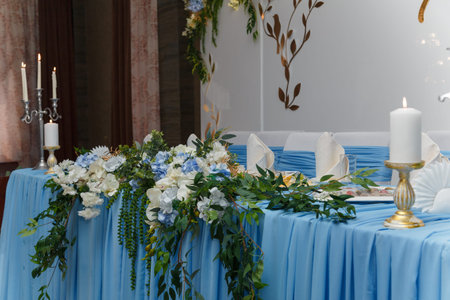 Decorated blue wedding presidium, festive table and arch for just married, event organization. Beautiful flowers and burning candles.の写真素材