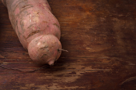 Raw dirty sweet potatoes, yam on wooden rustic brown table. Farm harvest, organic vegetables, shop local concept. Close up vegetarian foodの写真素材