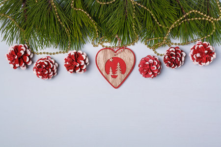 Merry Christmas, New Year postcard, template, pine tree branches, golden beads, wooden heart shaped toy, red painted cones. Copy spaceの写真素材