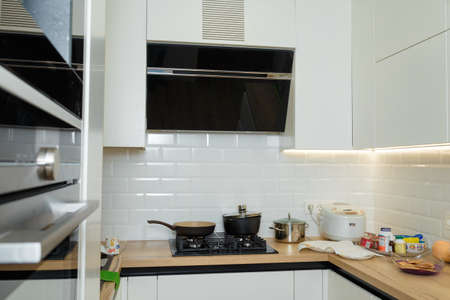 Izmail, Ukraine. March 2021. Modern kitchen interior, gas cooker with some dishware, kitchen hoods, multicooker, backlight under shelves.のeditorial素材