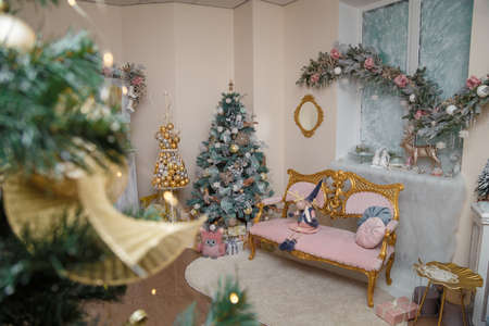 Izmail, Ukraine. December 2020. Merry Christmas decorated room. Festive interior with fir tree, pink sofa, wooden toys, icy roses. Wrapped presentsのeditorial素材