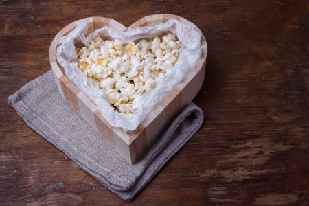 Wooden heart shaped box with popcorn on wooden rustic background. Close up shotcopy space.の写真素材