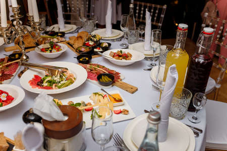 Festive table setting with vegetable salads, meat, cheese, bread and drinks. Family event celebration, anniversary, wedding or birthday.の写真素材
