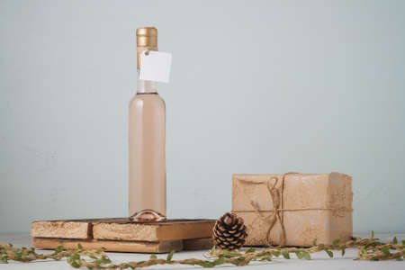 250 ml bottle of white or pink wine with blank label. Wrapped Christmas present, pine cones. Alcohol drink. copy spaceの写真素材