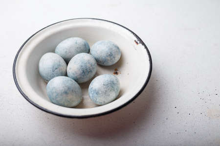 Easter eggs painted blue in white bowl on wooden background. copy spaceの写真素材