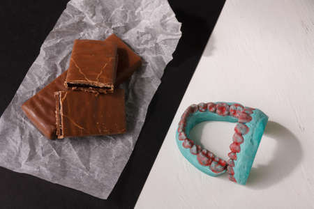caries prevention concept. Sweet danger for tooth. Healthy eating for teeth. Chocolate and jaw cast on black white background.の写真素材
