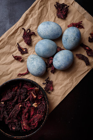 Beautiful DIY painted Easter eggs, dry Hibiscus tea in black bowl. Easter black wooden background....