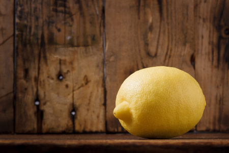 Fresh sweet sour lemon on wooden brown background with some dry autumn leavesの写真素材