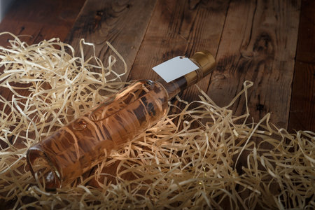 250 ml bottle of pink wine with blank label lying on wooden shavings, wooden table. Alcohol drink. Copy spaceの写真素材